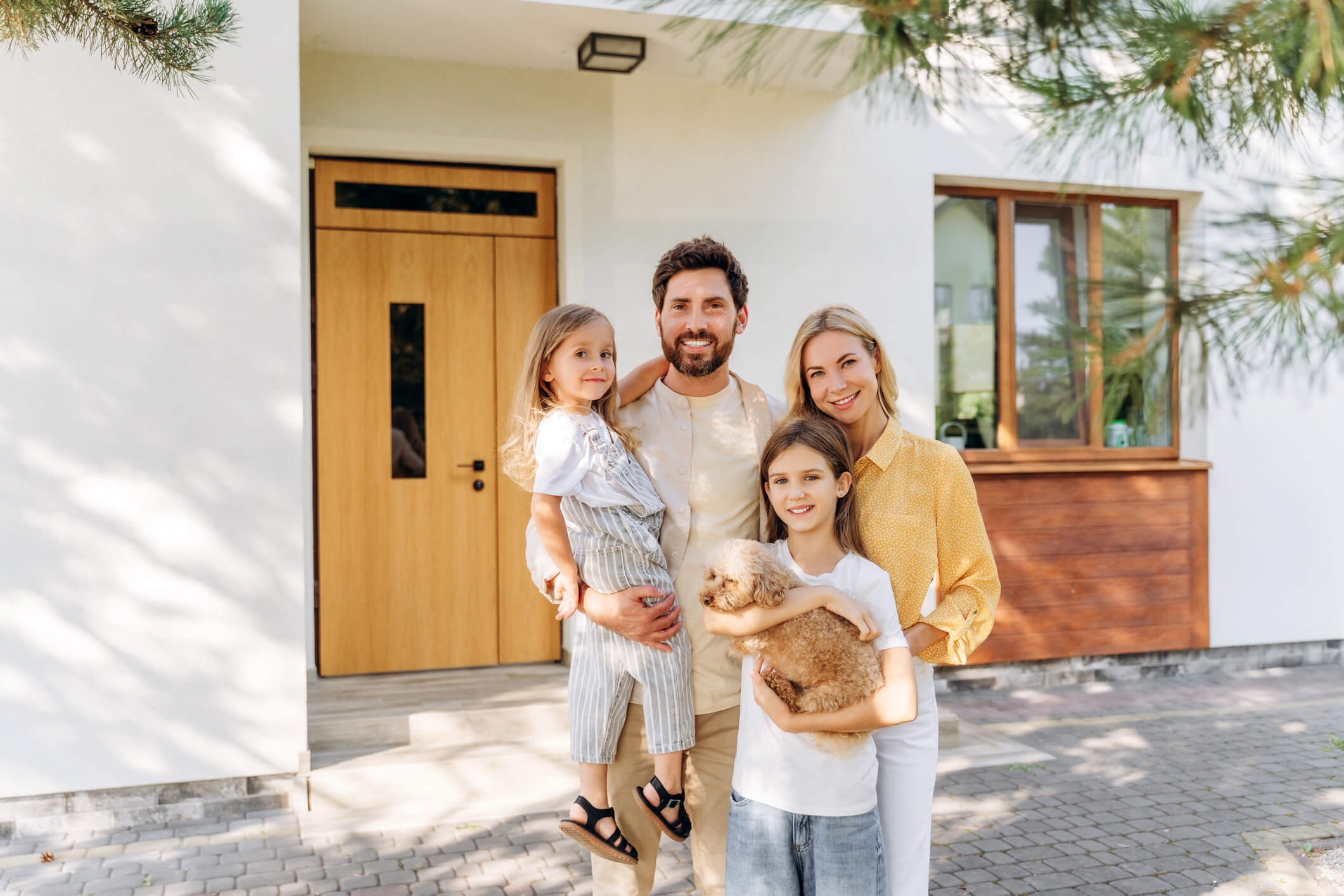 Family smiling in front of house
